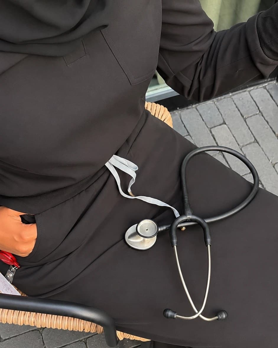 Close detail of the black scrub set: hip pocket, drawcord and a stethoscope