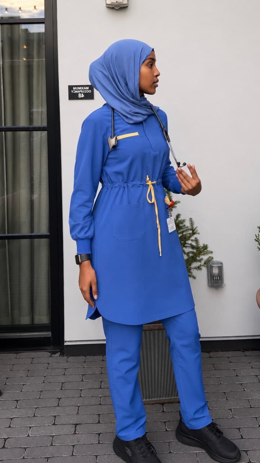 Nurse in a royal blue long-sleeve tunic scrub set with a drawcord waist